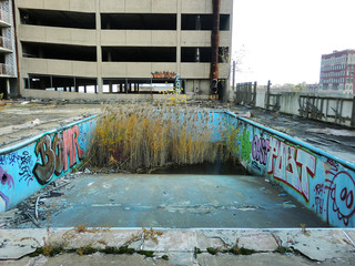 Abandoned old swimming pool with weeds growing in deep end - landscape color photo