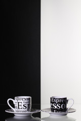 Black and white cups  of coffee on a glass table