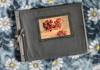 Старый фотоальбом на фоне скатерти с ромашками