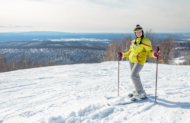 Fototapeta na wymiar Girl skier in a yellow jacket on top of a mountain