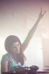 Fototapeta na wymiar Pretty female DJ waving her hand while playing music