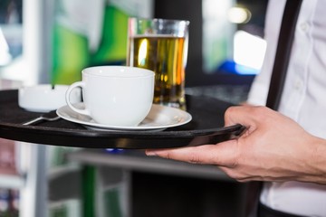 Waiter serving whiskey and a cup of coffee 
