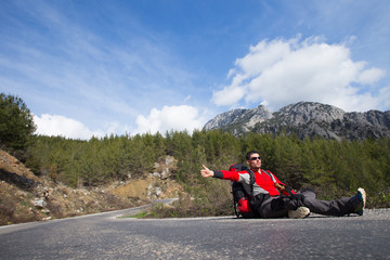 Hitchhiking traveler try to stop car on the mountain road