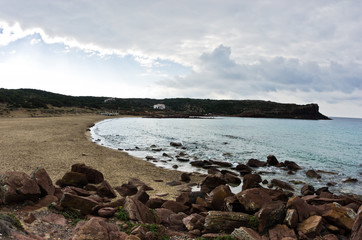 Fototapeta na wymiar Sandy beach with cliffs at the end in San Pietro island, Sardinia, Italy
