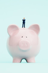 Miniature businessman and piggy bank.