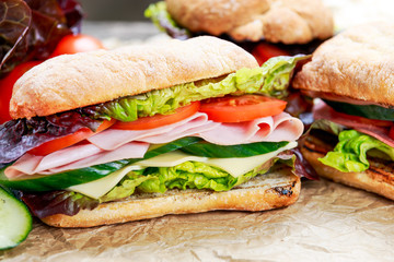 Sandwich with lettuce, tomatoes, cucumber, red onion, salami, ham, cheese