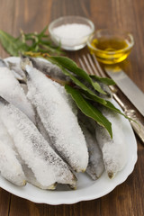 sardines in ice on white dish on brown background
