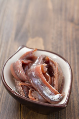 anchovies in dish on brown wooden background