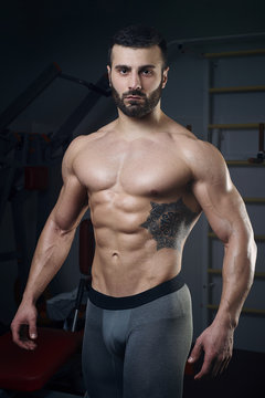 Men's physique athlete standing without t-shirt in the gym
