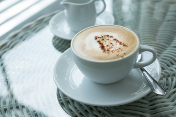 White cup of cappuccino stands on the table, selective focus