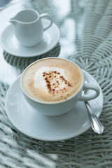 White cup of cappuccino stands on the table, selective focus