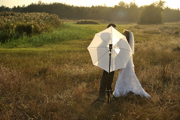 Just Married Couple with Photographer's Umbrella in a field