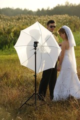 Just Married Couple with Photographer's Umbrella in a field