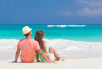Couple in bright clothes sitting at tropical beach