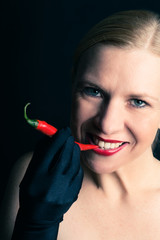 Blonde woman bites into a red chili