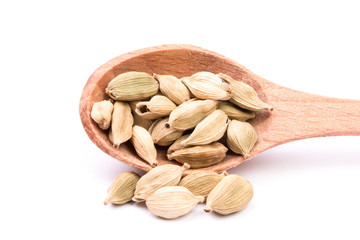 Cardamom seeds in the wooden spoon on white background
