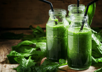 Healthy spinach smoothies, detox drink in glass bottles on the o