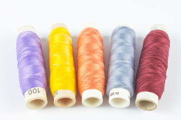 Coloured bobbins of thread on white background 