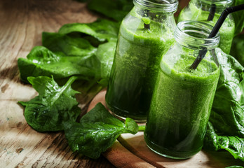 Healthy spinach smoothies, detox drink in glass bottles on the o