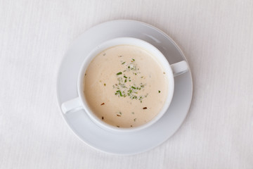 simple white cream soup with herbs in a cup handle on top of the menu isolated