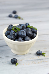 Bowl full of fresh blueberries on a wooden background
