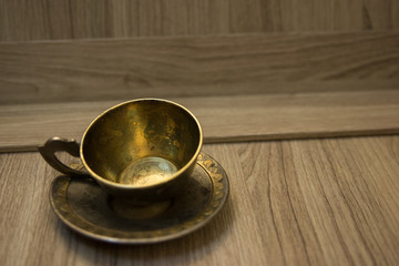 Old retro vintage copper coffee cup on wooden table