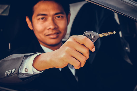 Business man showing key and sit in car