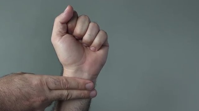 Man hands checks self pulse on a grey background. Concepts and ideas with copy space