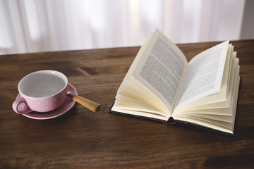 Cup of coffee with a book on wooden table