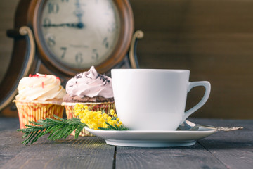 Closeup cup of tea and cupcakes on wooden table