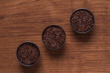 linseed in metal bowl on brown wooden table