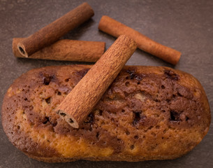 Cinnamon sticks and cake with jam on light brown background