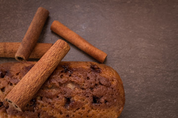 Cinnamon sticks and cake with jam on light brown background