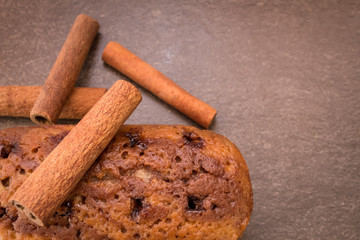 Cinnamon sticks and cake with jam on light brown background