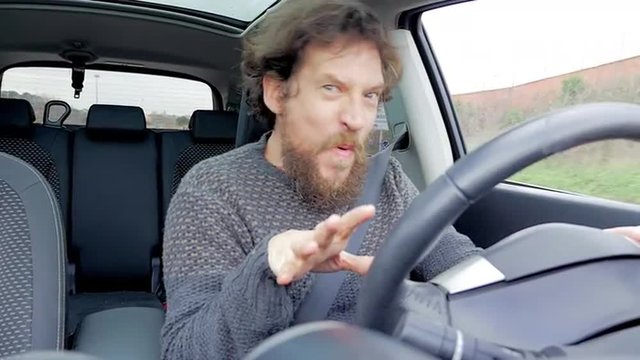 Happy hipster man dancing and singing in car looking camera slow motion