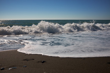 Waves wash over dark sand on the beach