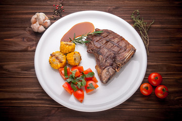 Beef steak with vegetables and seasoning on a wooden background