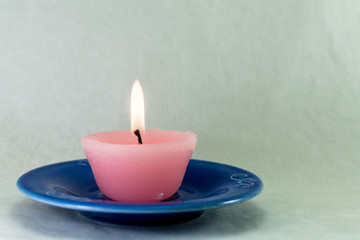 candela rosa accesa su piattino blu