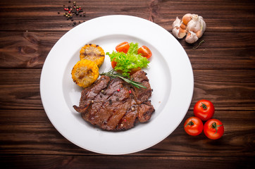 Beef steak with vegetables and seasoning on a wooden background