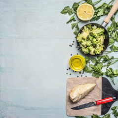 raw broccoli in a pan with herbs, lemon, celery root on a cutting board with a knife border ,place for text on wooden rustic background top view close up