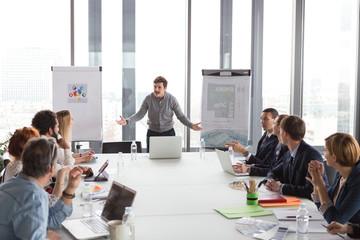 Hipster business man holding coffee cup and presenting the project in modern office.