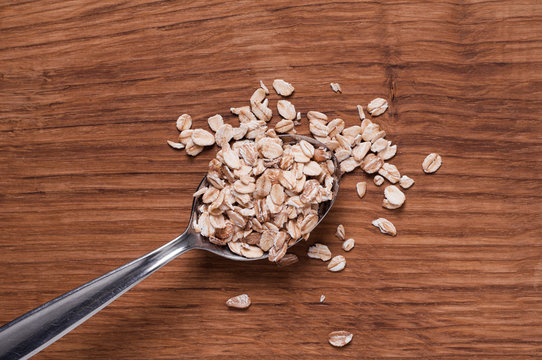 oat flakes on metal spoon on brown wooden table