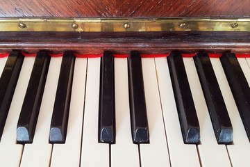 Picture of keys from an old fancy piano, with brown wood.