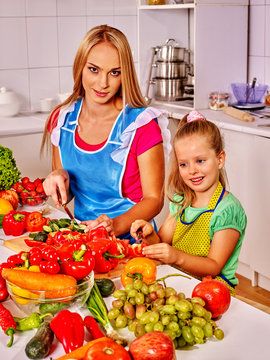 Mother and daughter prepare vegetarian salad at kitchen. Interior.