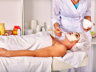 Obraz na płótnie Canvas Lying woman wearing medical hat middle-aged take facial and neck clay mask in spa salon. 