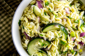 A freshly made orzo salad with cucumbers, red onion, parsley and feta cheese