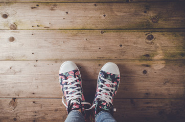 Female sneakers with floral pattern standing on wooden floor