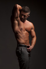 shirtless muscular man in pants posing in studio