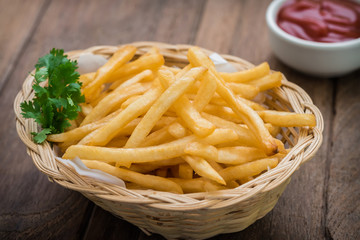 French fries in basket and ketchup on wooden table