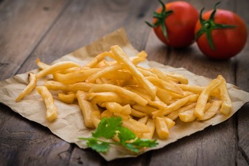 French fries on brown paper and fresh tomato